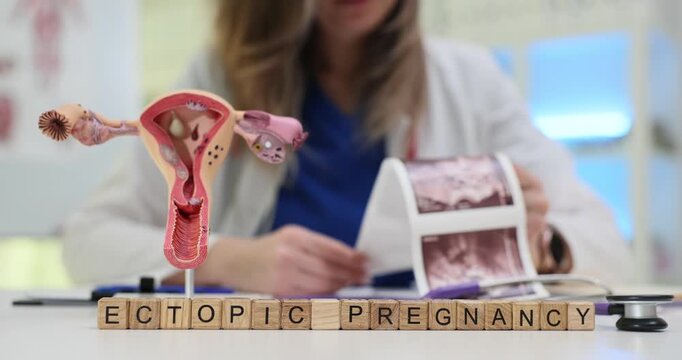 Wooden cubes display Ectopic Pregnancy highlighting abnormal embryo growth. Uterus anatomical model and scan image in doctor hand stress medical topic