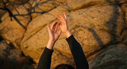Pair of Arms Extended Toward Light with Expressive Motion on Rocky Terrain with Granite Background and Branch Silhouettes