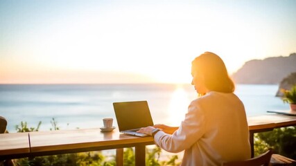 Woman working remotely at a seaside cafe during sunset, beautiful views, laptop lifestyle. - Powered by Adobe