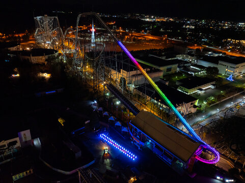 Aerial view of the Fujiyama Tower at night, its roller coaster tracks illuminated in vibrant rainbow hues against the dark landscape, Fujiyoshida, Yamanashi, Japan.