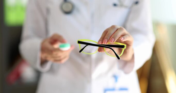 Pharmacist holds glasses and lens case preparing for customer consultation. Movement shows precision creating focus on professional eyesight stuff