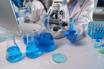 Scientist holding test tubes with blue liquid in laboratory