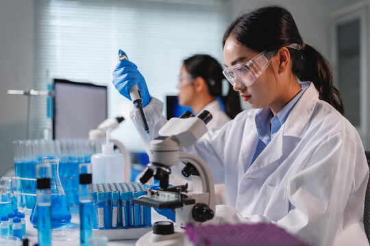 Scientist using micropipette and microscope in laboratory research
