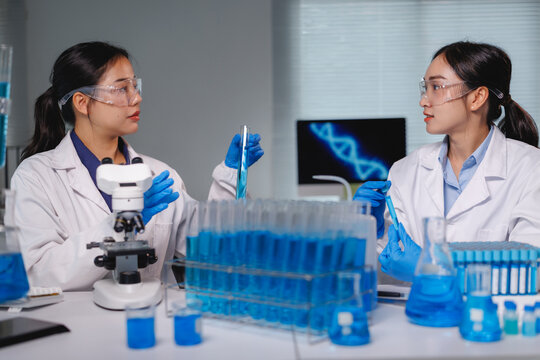 Scientists working with test tubes and microscope in laboratory - Powered by Adobe