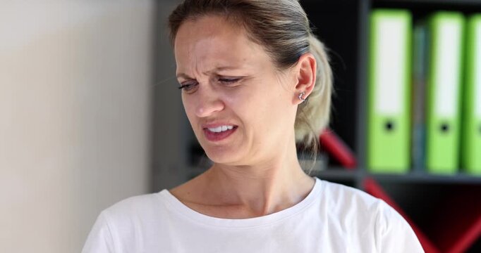 Blonde woman smells armpit reacting with unpleasant grimace creating disgusted expression. Female head turns slightly away while sensing bad odor