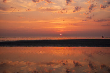 sunset over the sea and a silhouette of a single person