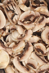 A full-frame close-up shot of a large pile of freshly sliced mushrooms, ready for cooking