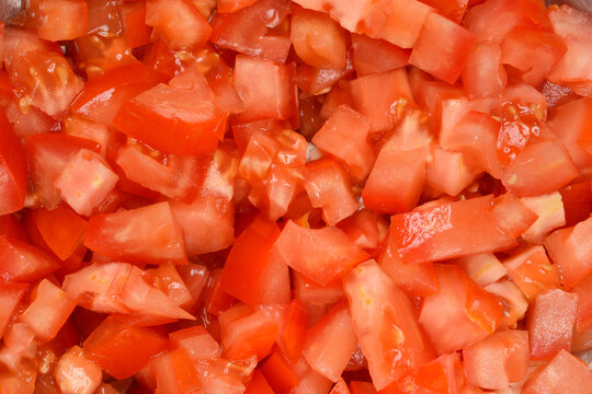 A close-up, top-down view of a pile of freshly diced tomatoes, showcasing their vibrant red color and texture
