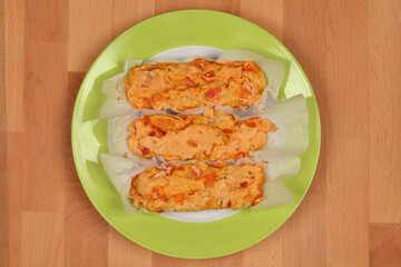 Three baked Sardinian tomato focaccias (Sa Costedda) on a green plate, placed on a wooden background