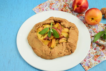 Nectarine galette with sage and honey on blue background