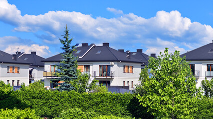 Terraced family homes in newly developed housing estate. The real estate market in the suburbs. New single family houses in a new development area. Residential homes with modern facade. 