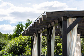 The terrace behind the house has visible beam connections, the roof is covered with polycarbonate.