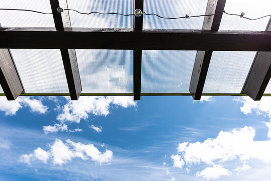 The terrace behind the house has visible beam connections, the roof is covered with polycarbonate.