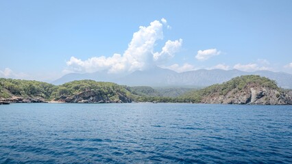 Coastal landscape with green hills and blue sea.