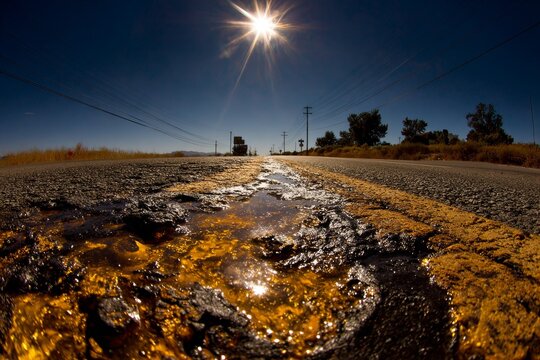 Melting asphalt on sunny road reflecting bright sunlight