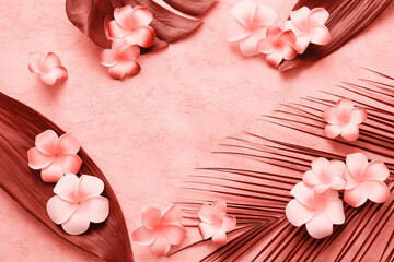 Frame made of plumeria flowers with tropical leaves on coral grunge background