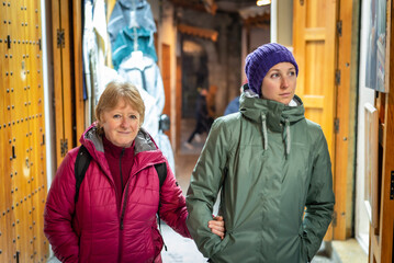 Senior mother and adult daughter walking through a colorful shopping street at night in Tangier,...