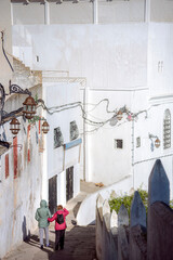 Senior mother and adult daughter walking together along whitewashed narrow streets of Tangier...