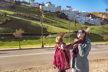 Senior mother and adult daughter walking together on the seafront promenade in Tangier, Morocco,...