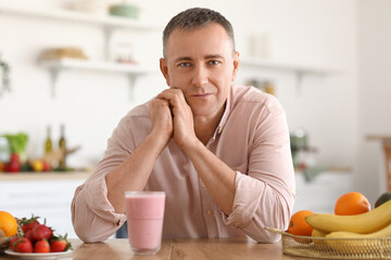 Mature man with glass of fresh fruit smoothie in kitchen