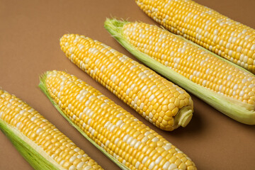 Fresh corn cobs on brown background