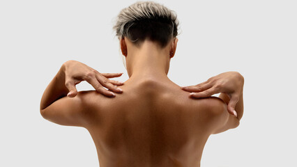Back view of woman with short hair touching shoulders with relaxed fingers. Concept of body care,...