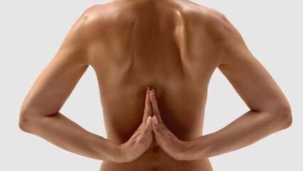 Bare back with arms in reverse prayer pose on light background. Concept of yoga, rehabilitation,...