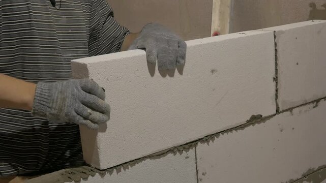 Worker laying foam concrete blocks with precision, applying glue for a seamless construction process. laying and gluing foam concrete blocks. build house man concept. Adhesive concept