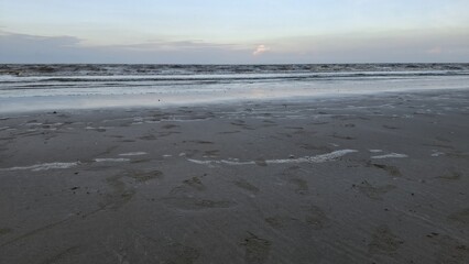 Obraz premium Serene ocean waves lapping on sandy beach coastal nature scene tranquil evening wide-angle view relaxing concept