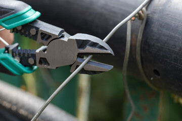 Cutting pliers and cable. A cutter is cutting electrical wire or cable. Cutting wires with...