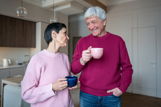 Retired husband enjoys listening to wife stories while sharing tea coffee. Happy senior couple talk at home, supportive marital routine, elderly family trusting relationship, spousal emotional support - Powered by Adobe