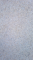 Small beige and grey gravel stones forming textured surface background. Seamless texture background. Construction material and urban design concept