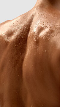 Close up of female muscular back with water drops on skin surface. Concept of body care, hygiene, wellness, medical examination, dermatology, and aesthetic treatment.