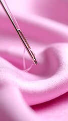 Close-up of a needle and thread piercing pink fabric