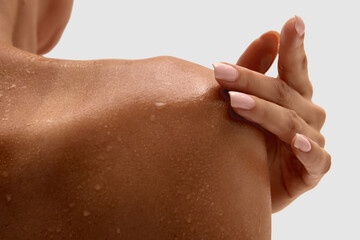 Close up of female shoulder with wet skin touched by hand with manicured nails. Concept of...