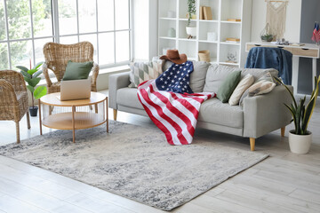 Interior of living room with laptop on coffee table, grey sofa and USA flag