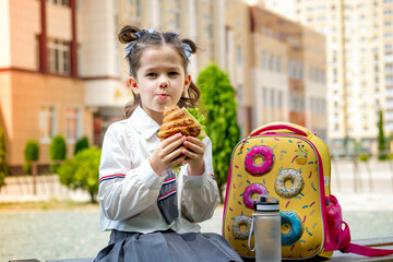 school meals, a schoolboy girl has lunch on the street with a hamburger, a child eats a sandwich...