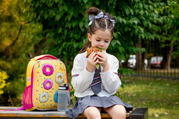 school meals, a schoolboy girl has lunch on the street with a hamburger, a child eats a sandwich...