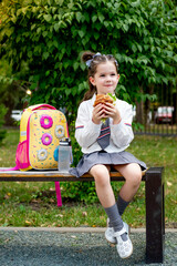 school meals, a schoolboy girl has lunch on the street with a hamburger, a child eats a sandwich...