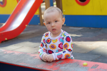 The baby plays on the playground in the park on a sunny day