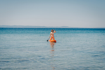 Woman kneeling on paddle board enjoying paddleboarding in the sea