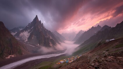 Mountain valley at sunset, tents nestled in the valley. Dramatic clouds and peaks