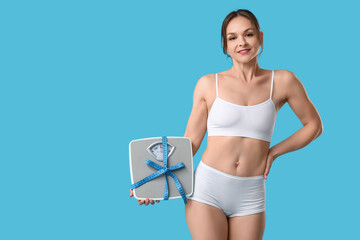 Young woman in underwear with scales and measuring tape on blue background. Diet concept
