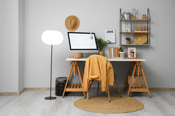 Stylish workplace with modern PC monitor and calendar near grey wall