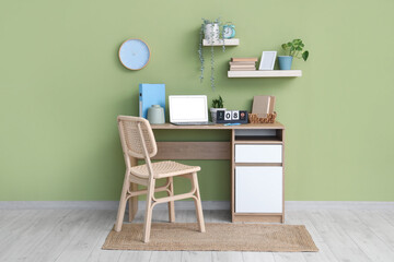 Stylish workplace with modern laptop, calendar and books near color wall