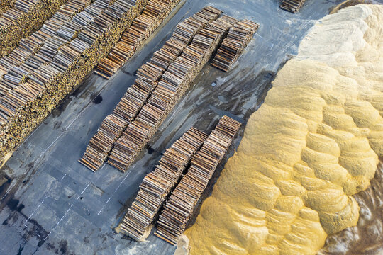 Aerial view of stacks of logs and piles of wood chips create an intricate pattern of textures and tones, showcasing the scale of the lumber industry, Graz, Styria, Austria.