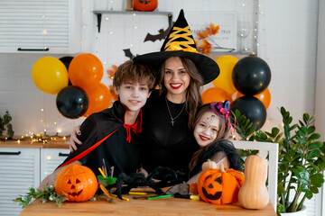 Happy family preparing for Halloween. Mother and children in carnival costumes at home in the...