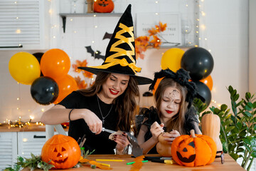 A happy family is getting ready for Halloween. Mother and child daughter in carnival costumes at...