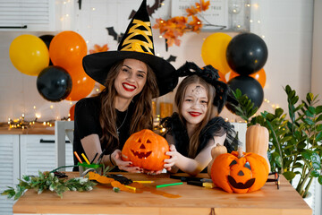 A happy family is getting ready for Halloween. Mother and child daughter in carnival costumes at...