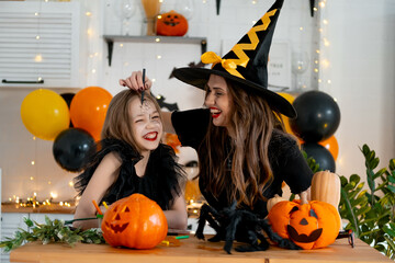A happy family is getting ready for Halloween. Mother and child daughter in carnival costumes at...